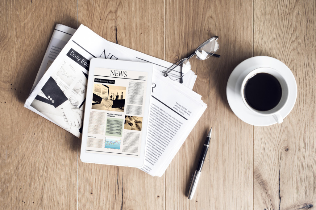 Newspaper with tablet on wooden table
